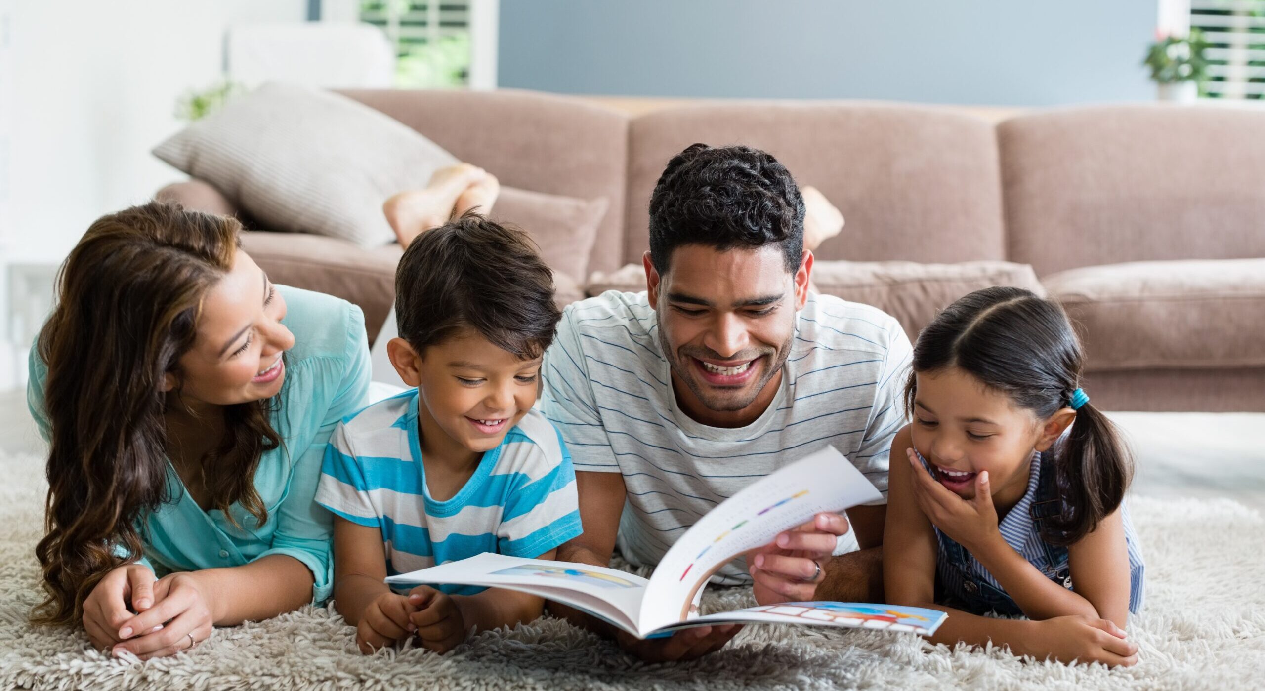 mother father young girl young boy reading a book together and smiling