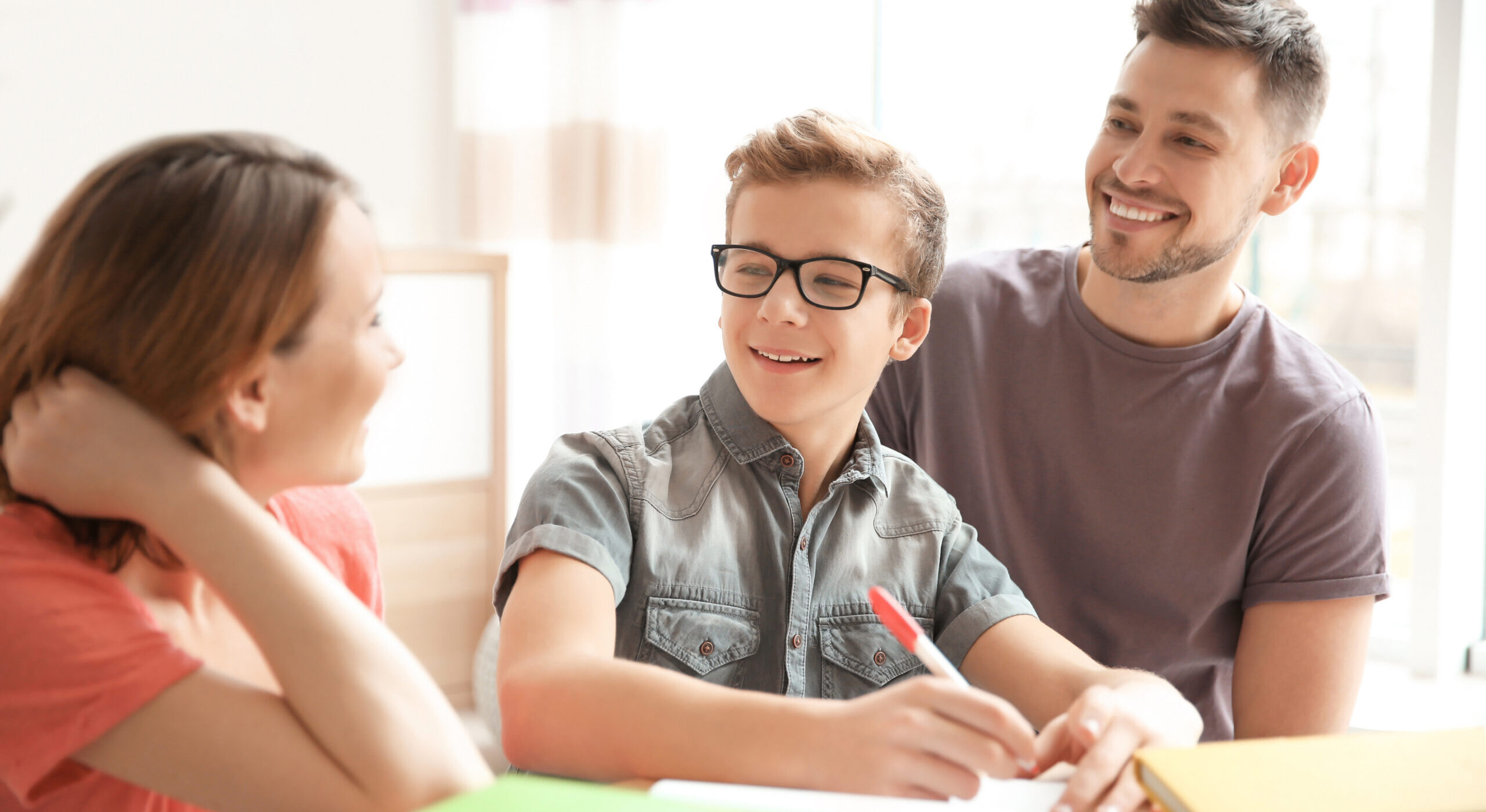 mother father and teen boy working on homework