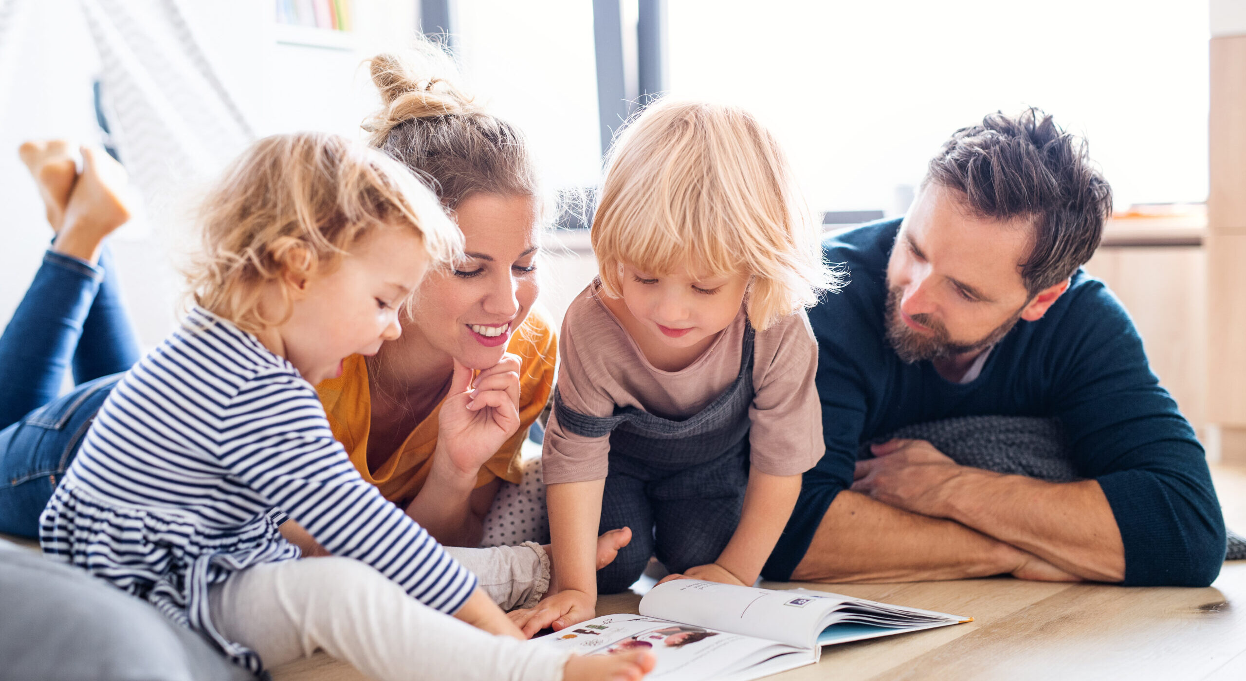 mother father two young children reading happily